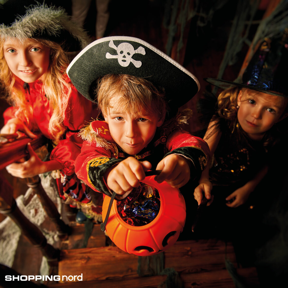 Symbolfoto: Drei Kinder in Halloweenkostümen halten Behälter für Süßigkeiten.