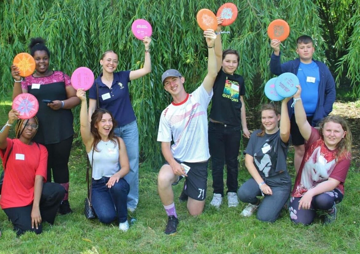 Teilnehmerinnen und Teilnehmer der Hobby Lobby Steiermark halten bunt gestaltete Scheiben im Garten hoch.