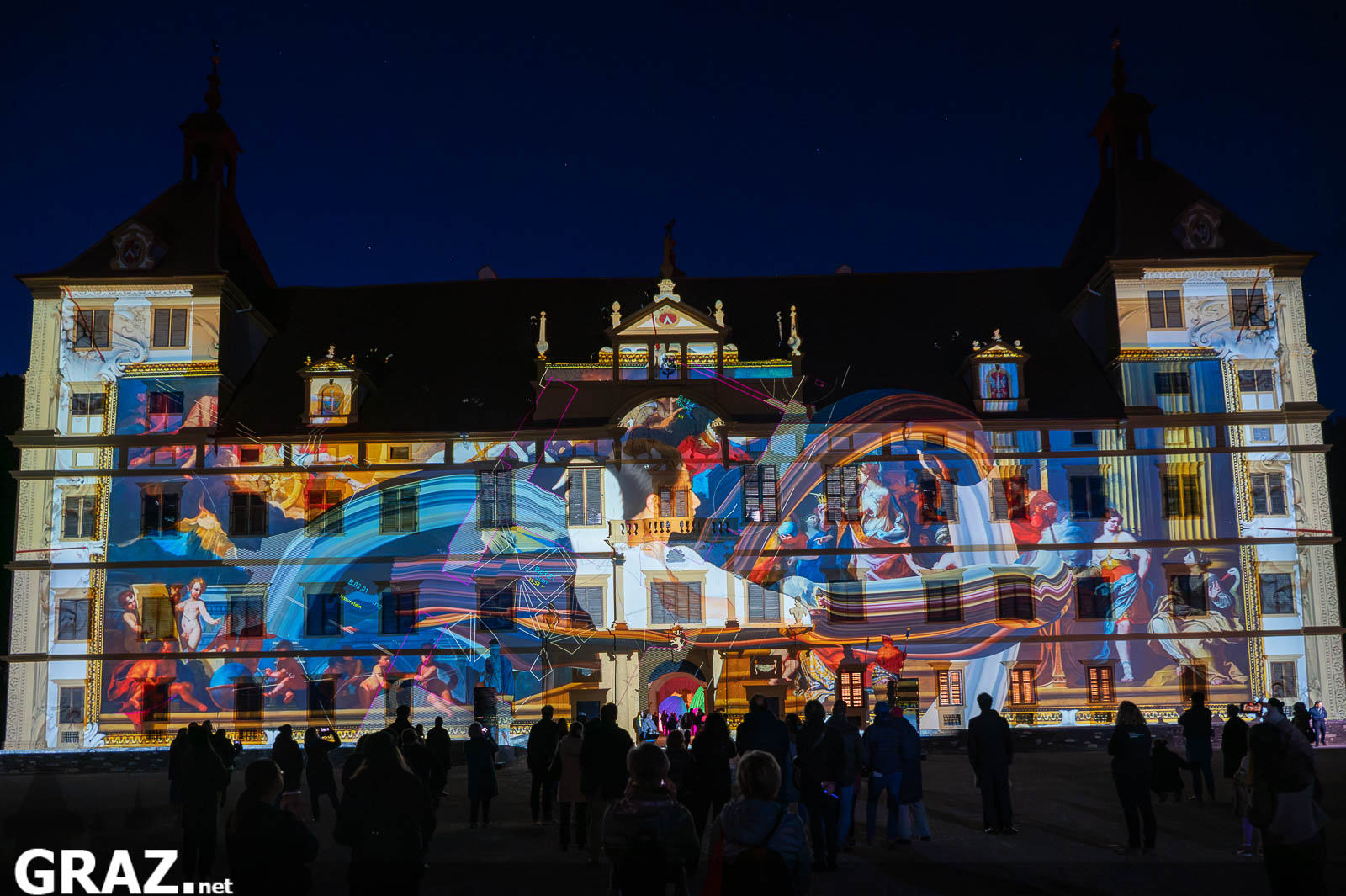 Blaue und rote Bildformen von Daniel Rossas „Kadenzen“ auf der Fassade von Schloss Eggenberg, davor das Publikum.