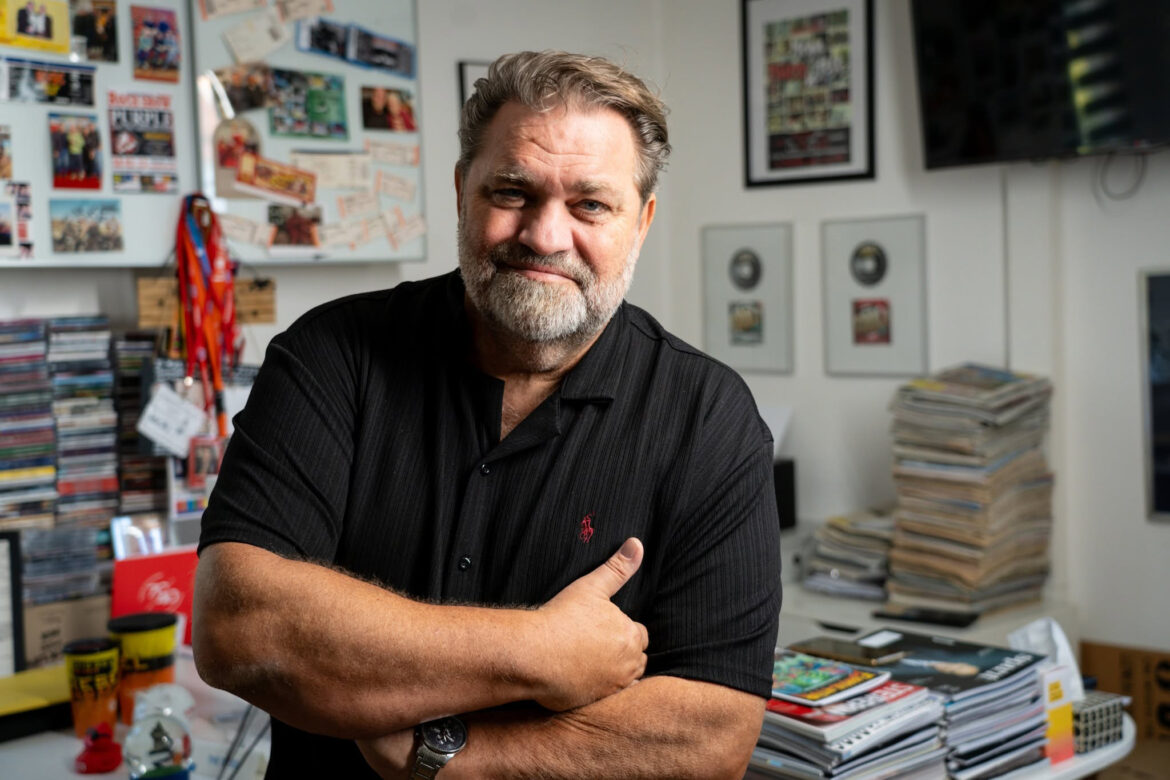 Michael Hüttler in seinem Büro vor Plakaten, CDs und Zeitschriften